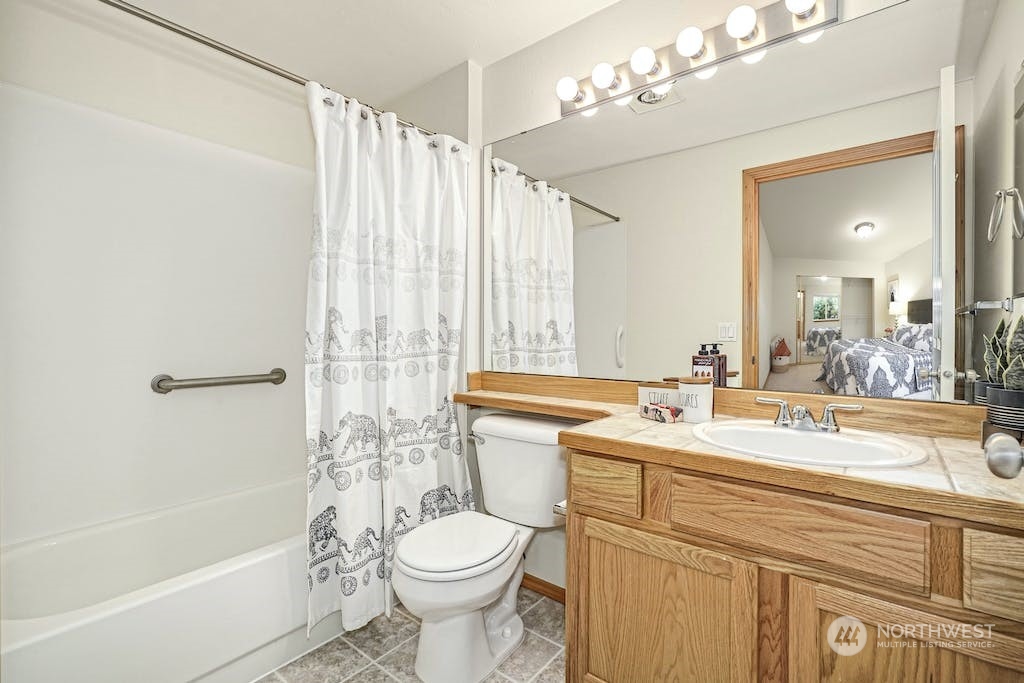 1009 112th Street Southeast, Unit E104 Everett, WA 98208 - Photo 13 of 24 a bathroom with a sink a toilet a mirror a bathtub and shower