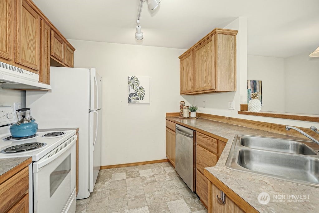 1009 112th Street Southeast, Unit E104 Everett, WA 98208 - Photo 6 of 24 a kitchen with stainless steel appliances granite countertop a refrigerator and a sink