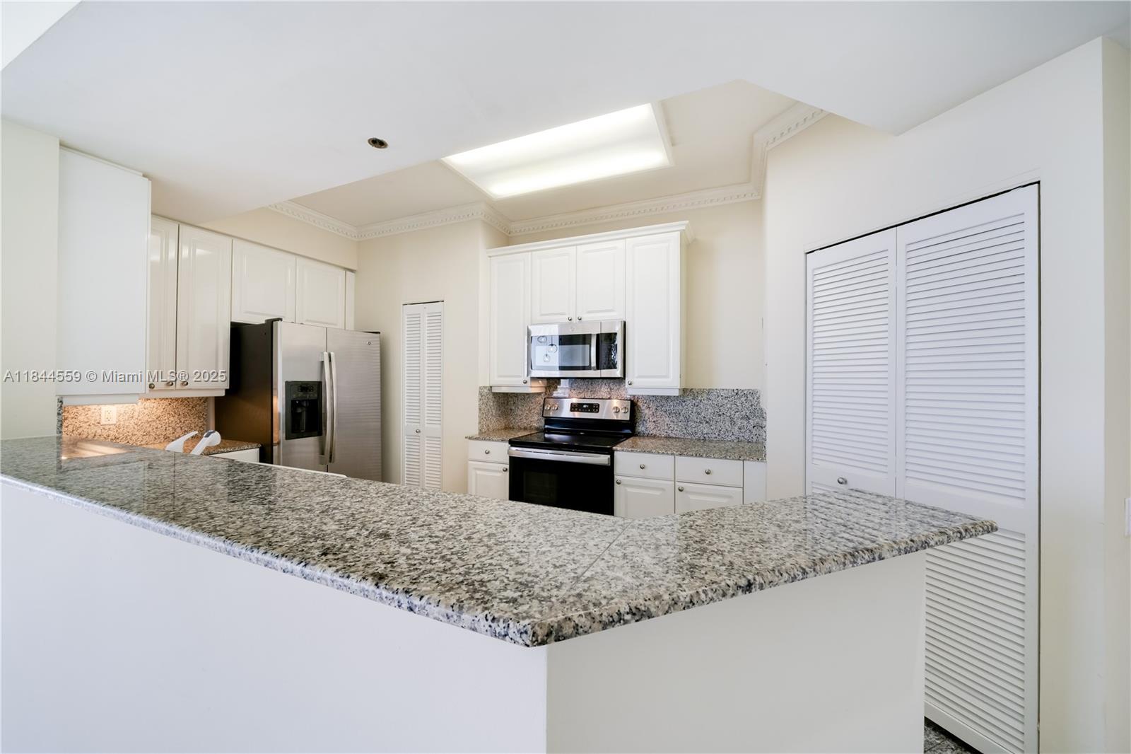 888 Brickell Key Drive, Unit 1912 Miami, FL 33131 - Photo 9 of 37 a kitchen with kitchen island granite countertop a sink and refrigerator