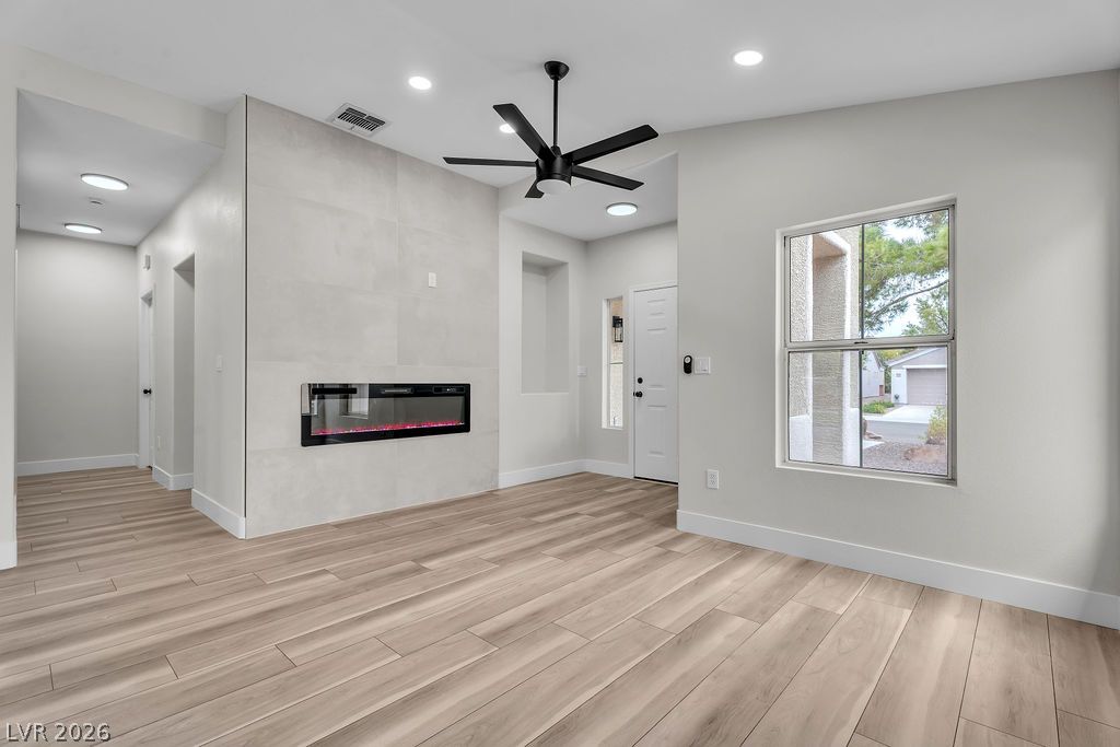 2139 Chapman Ranch Drive Henderson, NV 89012 - Photo 58 of 58 A modern electric fireplace with a tiled surround anchors this well-lit living space, featuring recessed lighting and durable wood-look flooring.