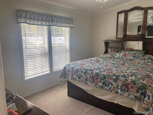 1661 Old Country Road, Unit 49 Riverhead, NY 11901 - Photo 9 of 11 a bed sitting in a bedroom next to a window