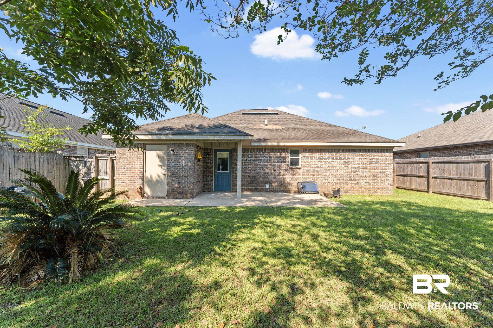 1549 Majesty Loop Foley, AL 36535 - Photo 24 of 25 Rear view of house with brick siding, a fenced backyard, a patio, and roof with shingles