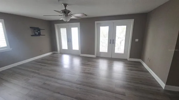 an empty room with wooden floor and windows