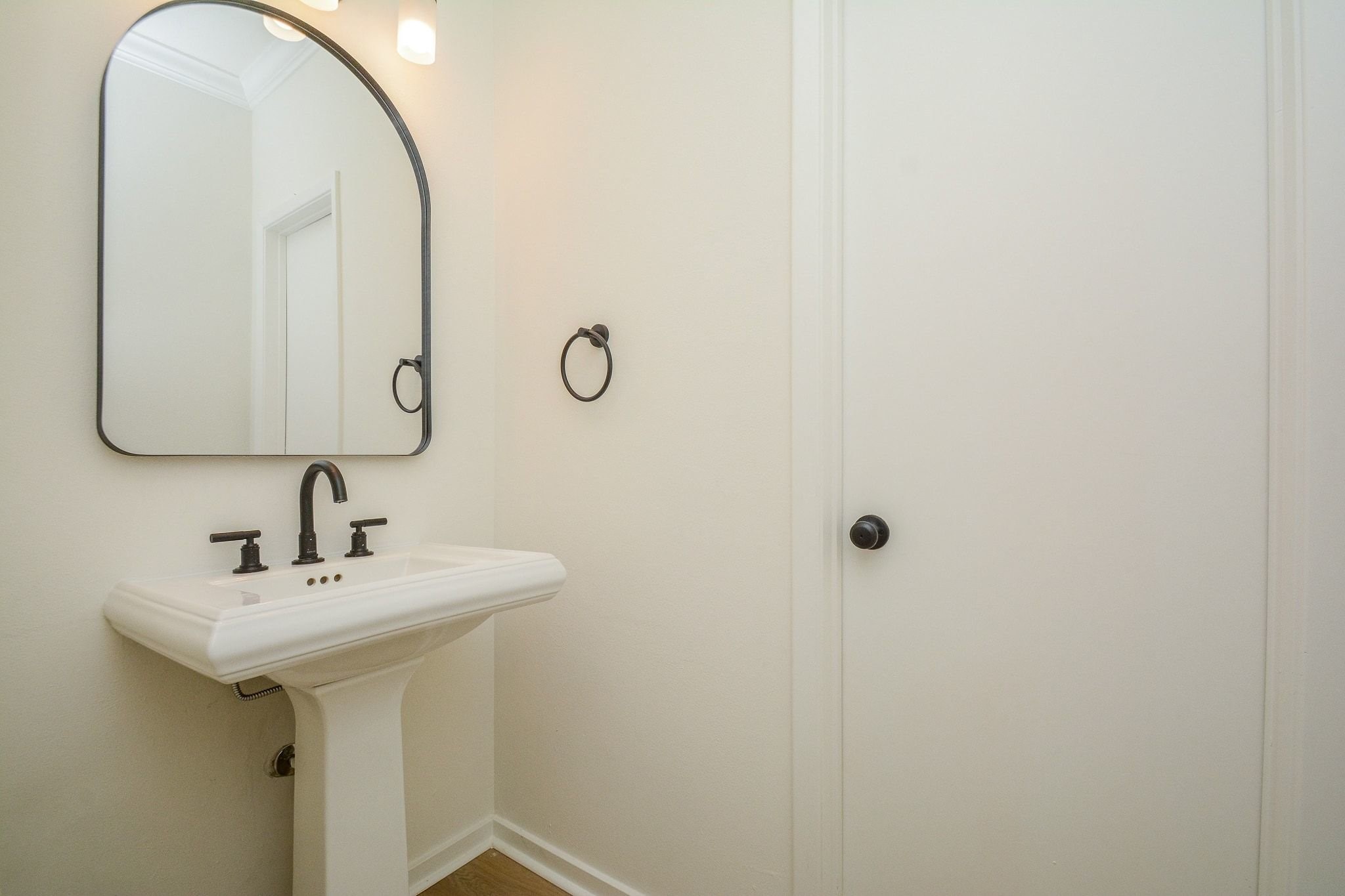 820 Harold Street Houston, TX 77006 - Photo 16 of 33 The powder bath is outfitted with a classic pedestal sink, an arched black-framed mirror, and matte black fixtures throughout.