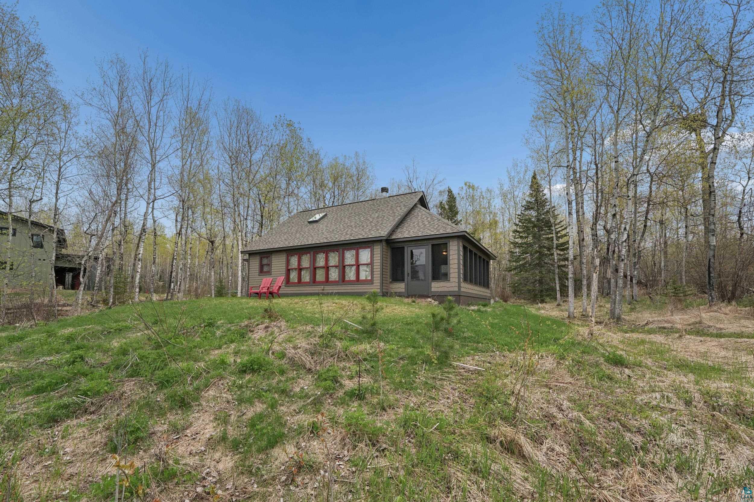 89095 West Romans Point Road Herbster, WI 54844 - Photo 25 of 30 Exterior residence featuring a screened porch, a gray-shingled roof, a skylight, and red-trimmed windows