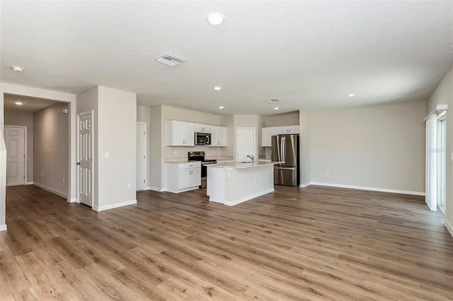 a view of kitchen with kitchen island wooden floor center island and stainless steel appliances