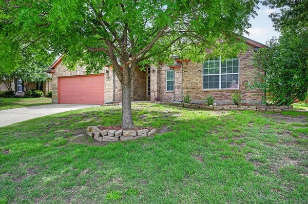 a front view of a house with a yard and tree