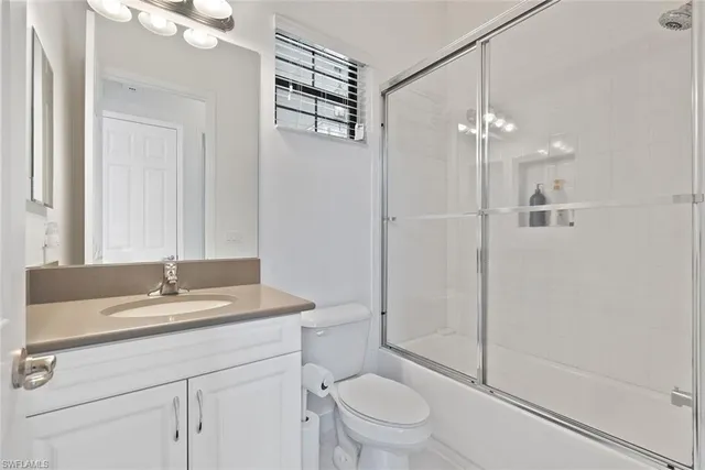 a bathroom with a granite countertop sink a toilet and shower