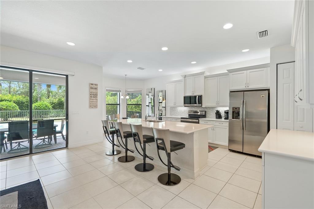 13750 Callisto Avenue Naples, FL 34109 - Photo 3 of 46 a kitchen with a dining table chairs and refrigerator