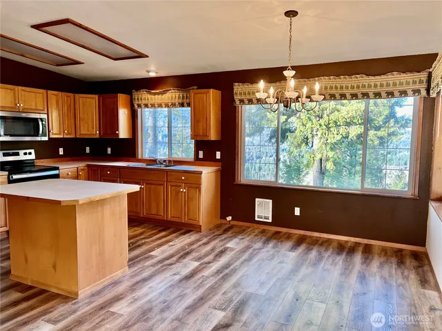 a kitchen with kitchen island granite countertop a stove a sink and a wooden floors