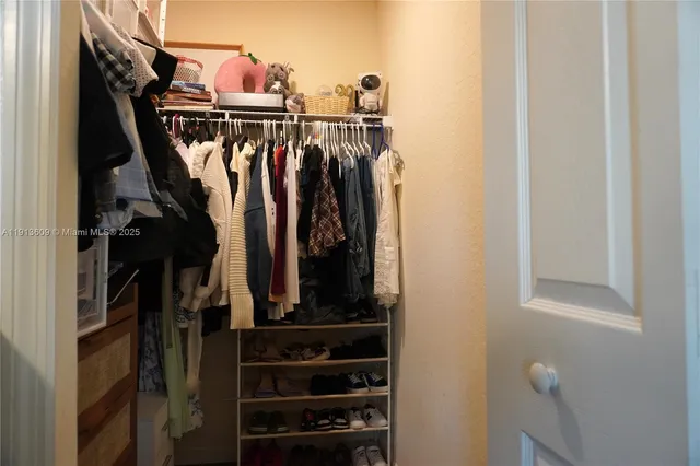 a view of walk in closet with clothes and shoes