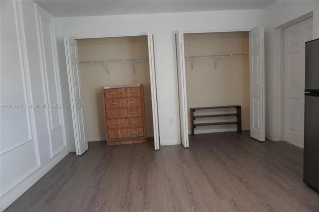 an empty room with wooden floor closet and windows
