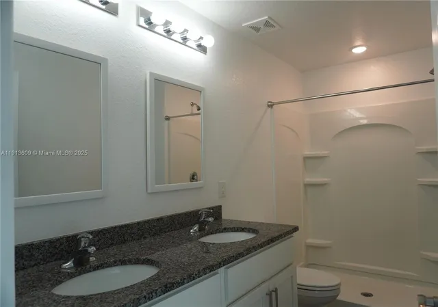 a bathroom with a granite countertop sink toilet and a mirror