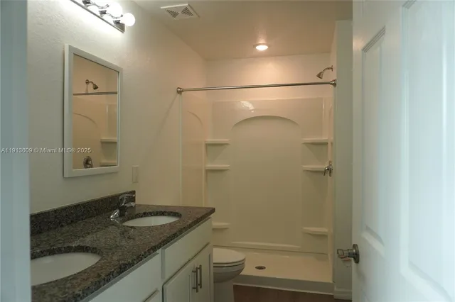 a bathroom with a granite countertop sink mirror vanity and toilet