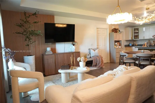 a living room with furniture a flat screen tv and kitchen view