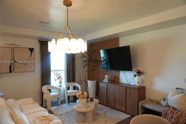 a living room with furniture a flat screen tv and a window