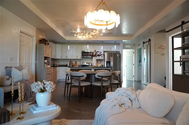 a living room with furniture kitchen view and a chandelier