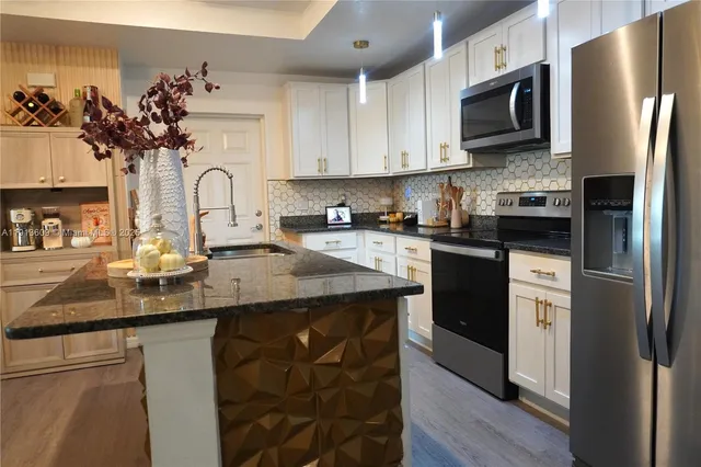 a kitchen with stainless steel appliances granite countertop a refrigerator a sink dishwasher a stove with wooden cabinets and floor