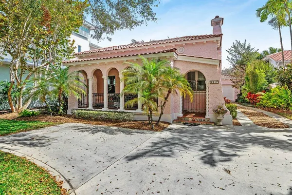 a view of a house with potted plants and a large tree