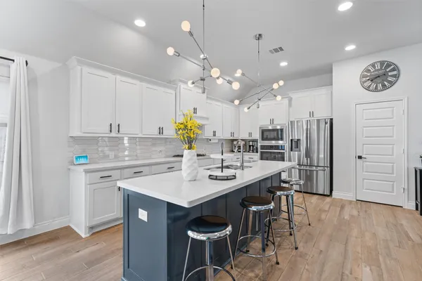 a kitchen with a sink a stove a refrigerator and white cabinets with wooden floor