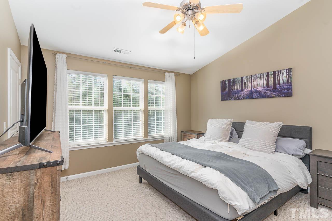 7859 Silverthread Lane Raleigh, NC 27617 - Photo 18 of 25 a spacious bedroom with a bed and a chandelier