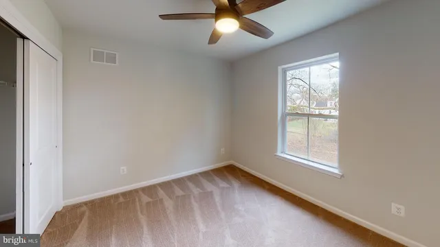 an empty room with a window and a fan