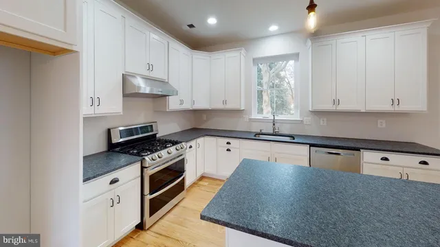a kitchen with granite countertop a stove sink and cabinets