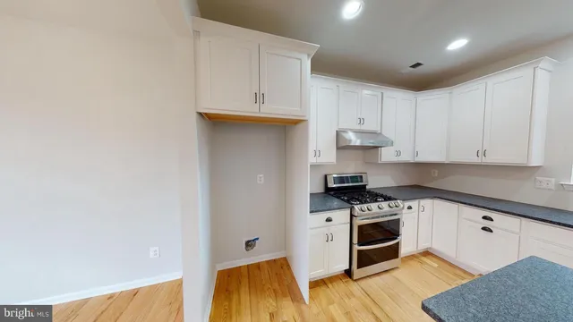 a kitchen with stainless steel appliances a stove a sink and white cabinets