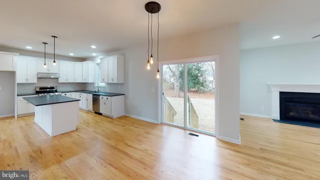 a kitchen with stainless steel appliances granite countertop a refrigerator a sink dishwasher a stove and white countertops with wooden floor