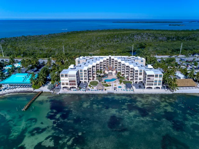 a living room with furniture a two large window and wooden floor