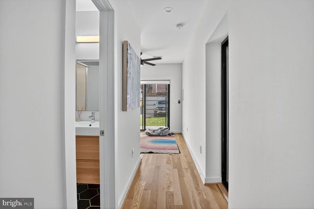 a view of a hallway with wooden floor and a bathroom
