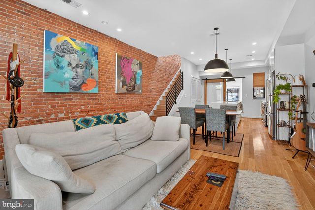 a living room with furniture kitchen view and a wooden floor