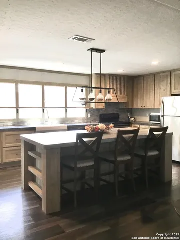 a kitchen with granite countertop a stove a sink and a refrigerator