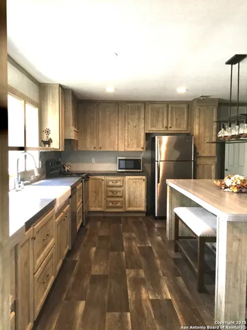 a kitchen with granite countertop a sink a counter top space stainless steel appliances and cabinets