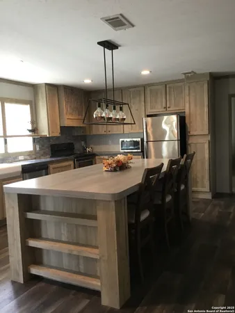 a kitchen with kitchen island a counter space a refrigerator and cabinets