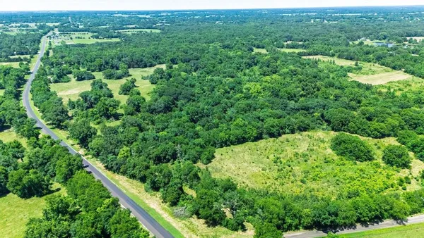 an aerial view of residential houses with outdoor space and trees