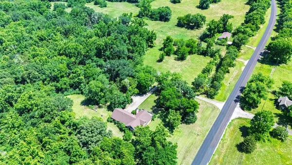 an aerial view of residential house with outdoor space and trees all around