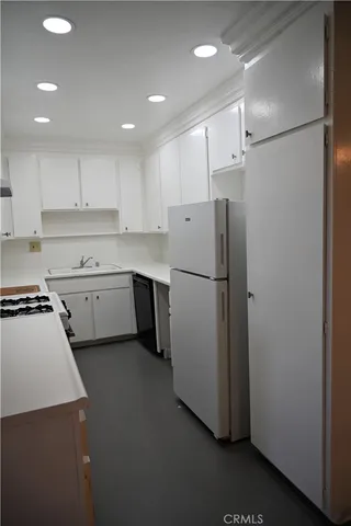 a kitchen with a refrigerator a stove top oven and white cabinets