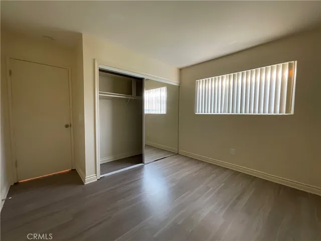 an empty room with wooden floor cabinet and windows