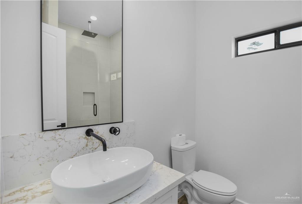 3730 East Davis Road Edinburg, TX 78542 - Photo 17 of 23 Bathroom featuring a tile shower, decorative backsplash, toilet, and vanity
