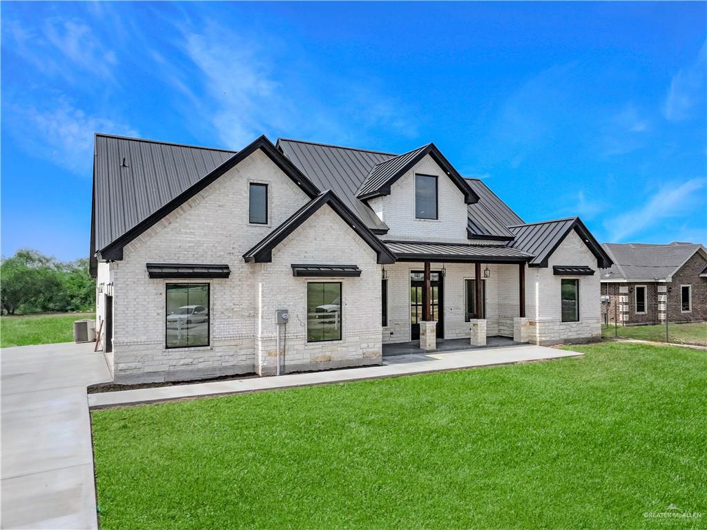3730 East Davis Road Edinburg, TX 78542 - Photo 2 of 23 View of front of house with a standing seam roof, a front lawn, metal roof, central air condition unit, and brick siding