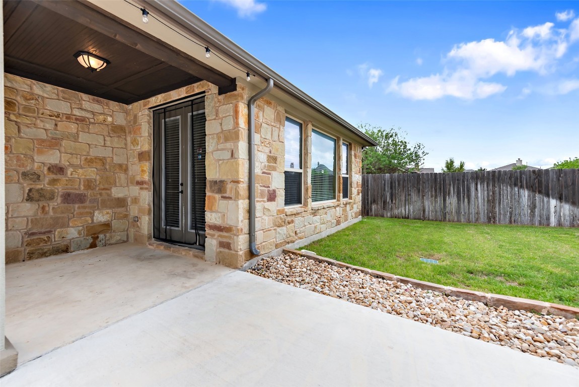 2000 Manada Trail Leander, TX 78641 - Photo 35 of 36 A spacious backyard patio, perfect for outdoor living, complements this charming stone-clad home.
