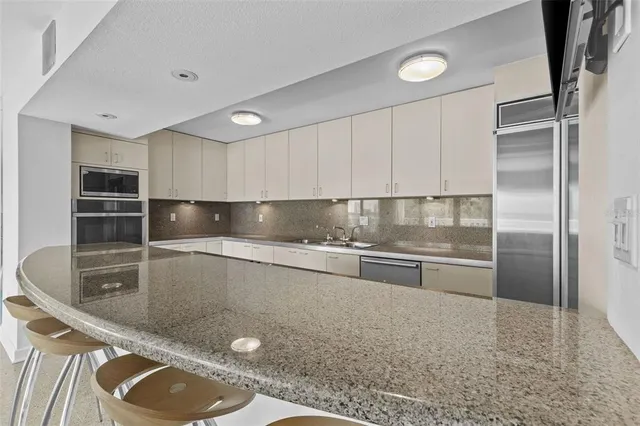 a kitchen with stainless steel appliances granite countertop a sink refrigerator and cabinets