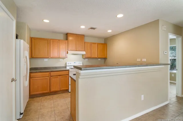 a kitchen with stainless steel appliances granite countertop a refrigerator a sink dishwasher and a stove with wooden floor