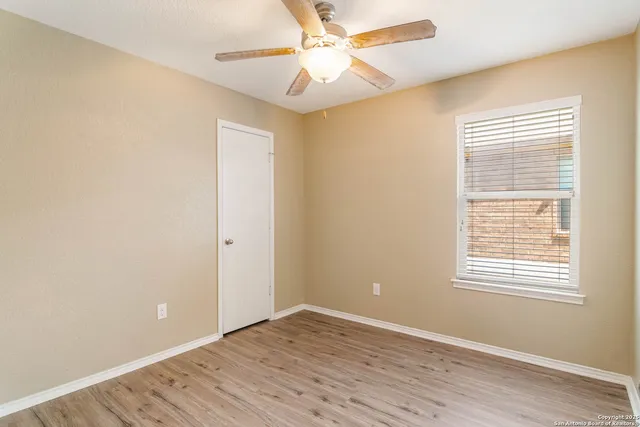 a view of an empty room with window and a ceiling fan