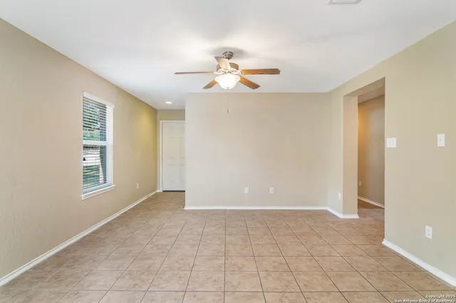 a view of an empty room with chandelier fan and a window
