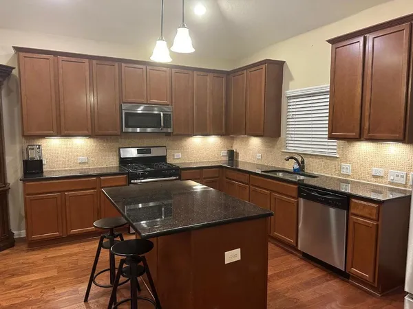 a kitchen with kitchen island granite countertop wooden cabinets and a refrigerator