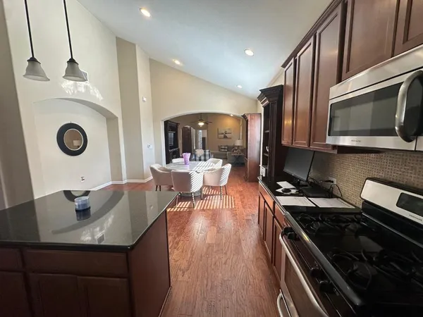a kitchen with a sink a stove and chairs with wooden floor