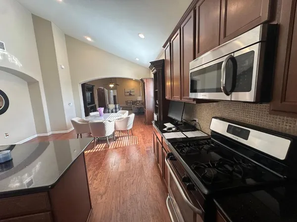 a kitchen with stainless steel appliances granite countertop a stove top oven a sink dishwasher and white cabinets