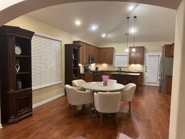 a kitchen with a dining table chairs refrigerator and cabinets